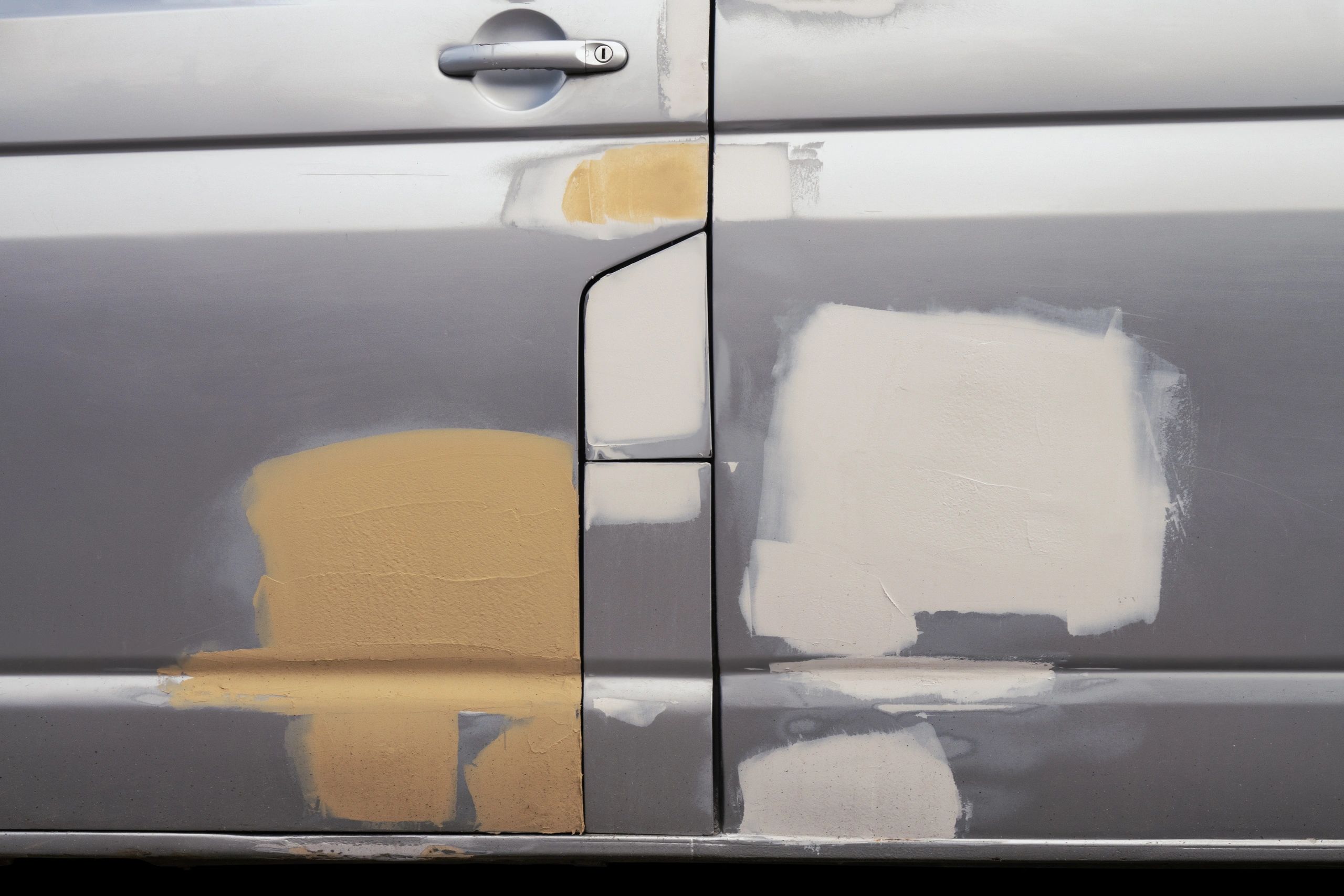 Close-up of a car door being primed and prepped for paint repair