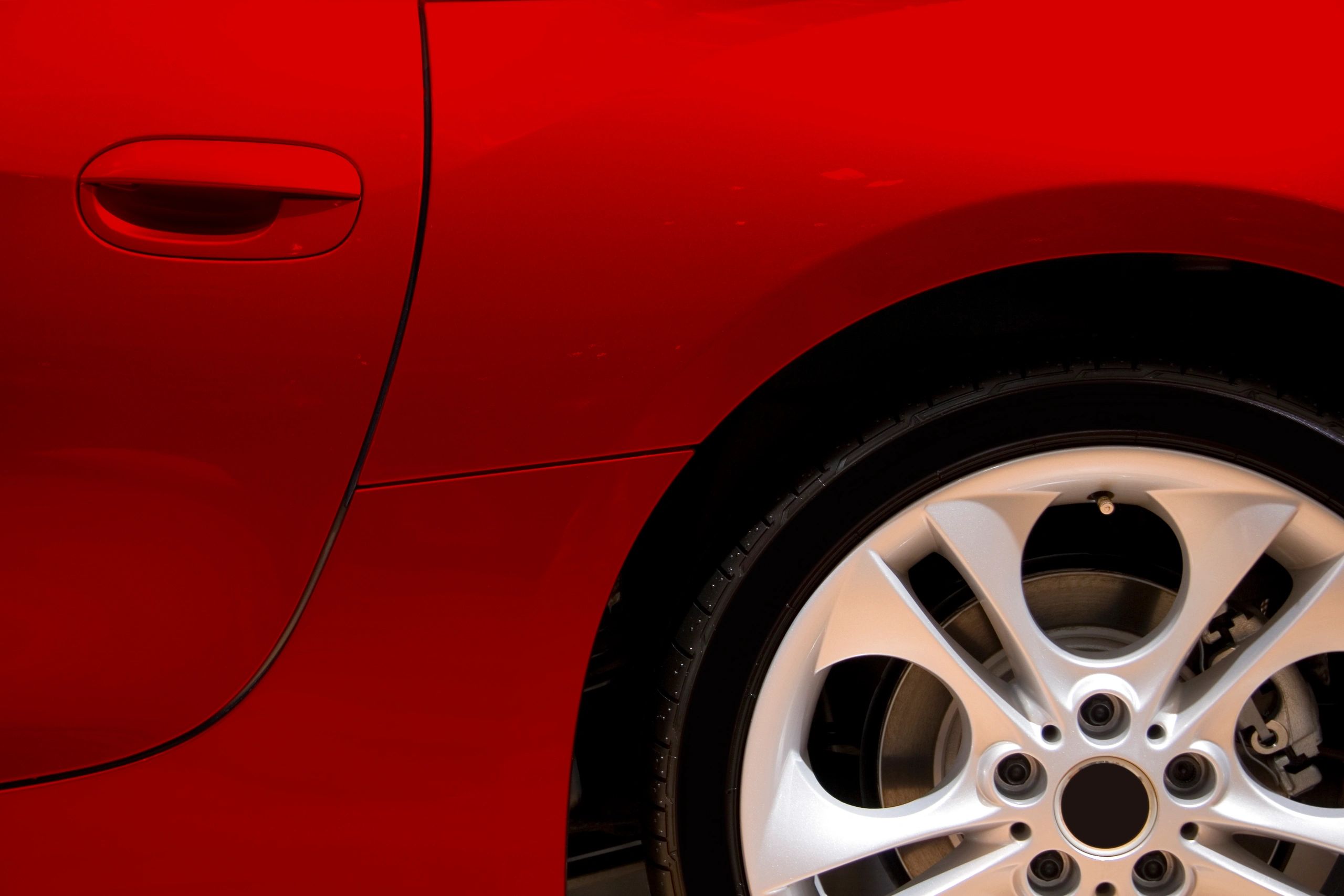 Glossy red car side reflecting light